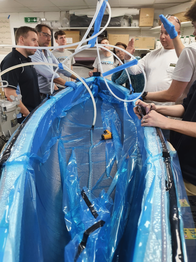 PRO-SET epoxy kayak vacuum infusion build in progress, with resin feed lines taped over a taped hull layup